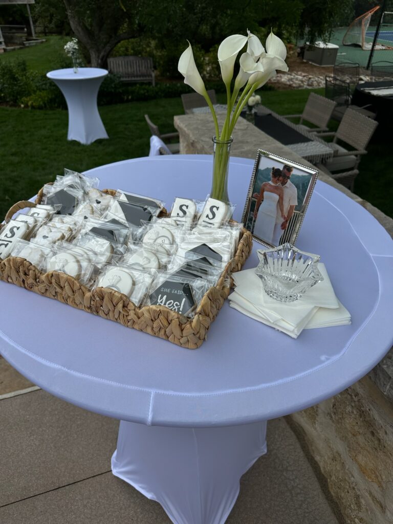Cookies with a bud vase and flowers set up for a classy engagement party.