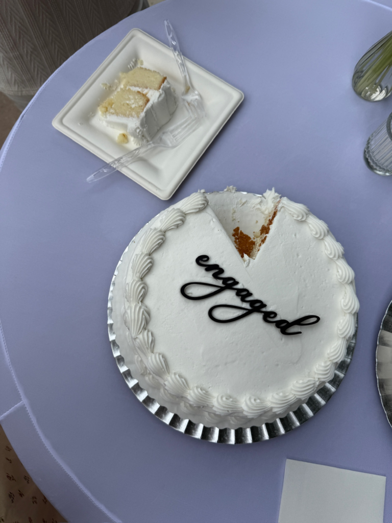 White round cake with "engaged" written in black icing.