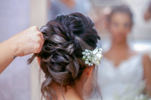 Wedding vendor completing an updo hairstyle on a bride.