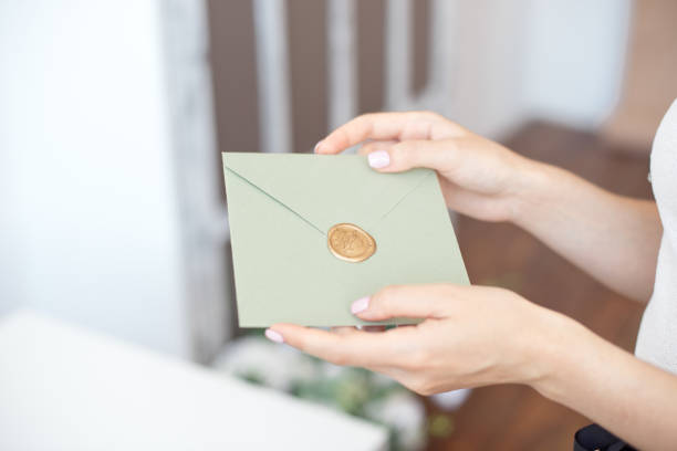 Close-up photo of female hands holding an envelope with a wax seal for wedding gift money.