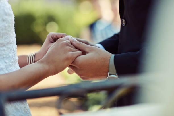 Cropped shot of a couple holding hands on their wedding day.